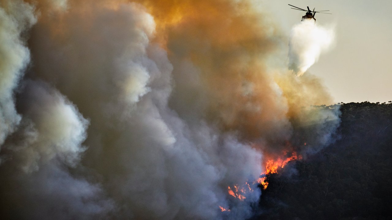 A skilful helicopter pilot and crew are water bombing fires A skilful helicopter pilot and crew are water bombing fires