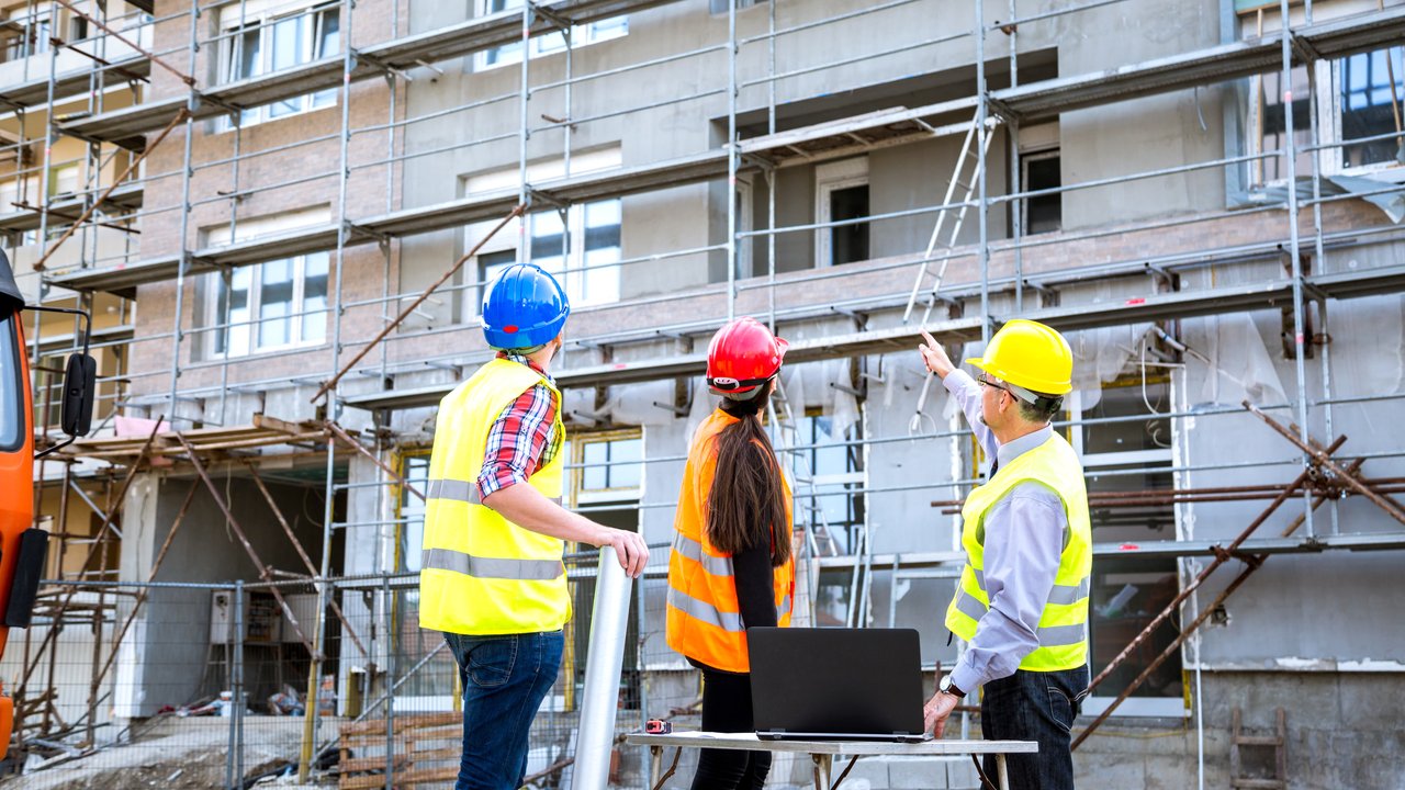 Engineers and workers confer on the construction site custom OCIP CCIP wrap-up policies and insurance packages for construction site projects