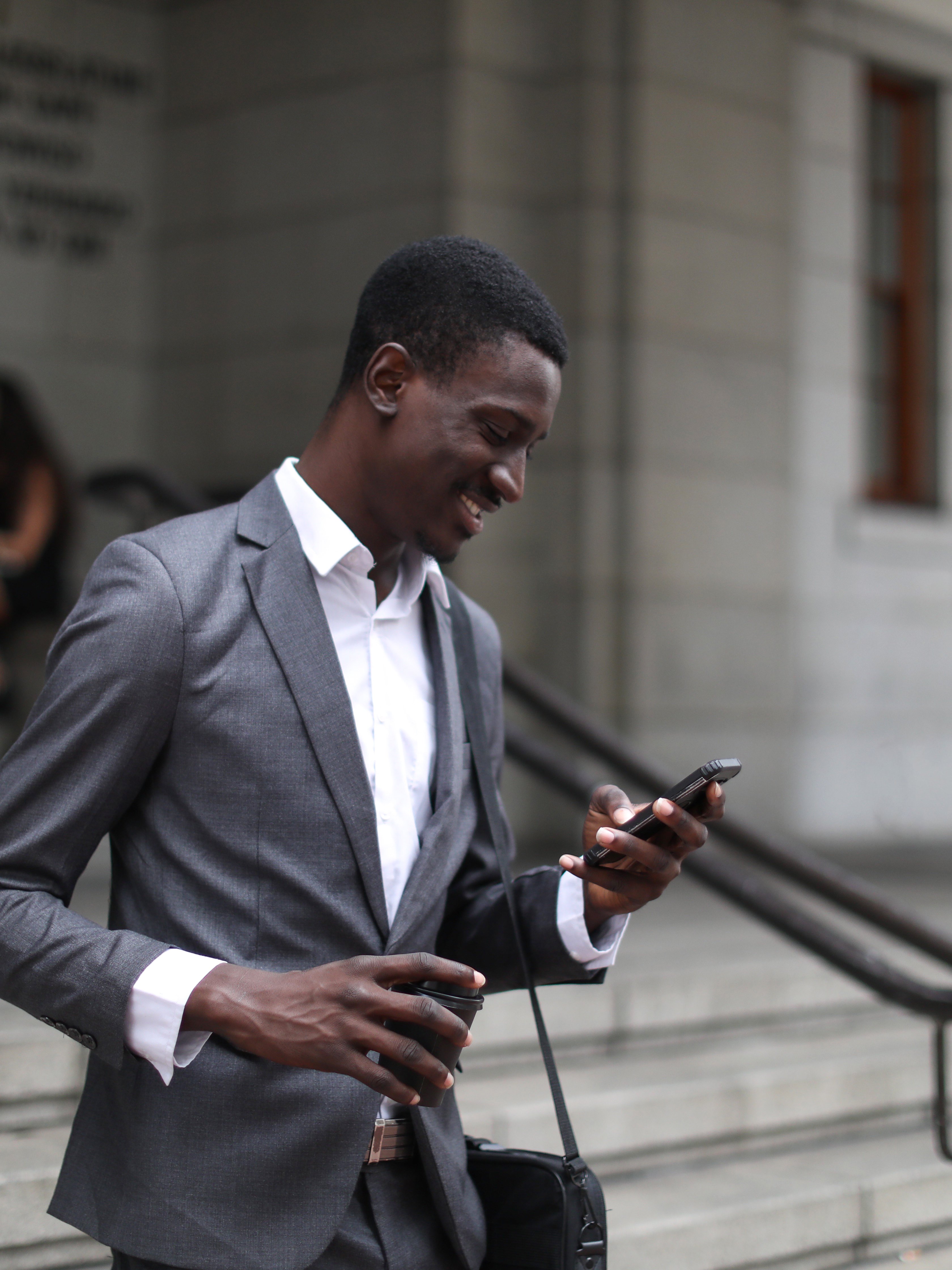 Man in suit looking at smartphone smiling