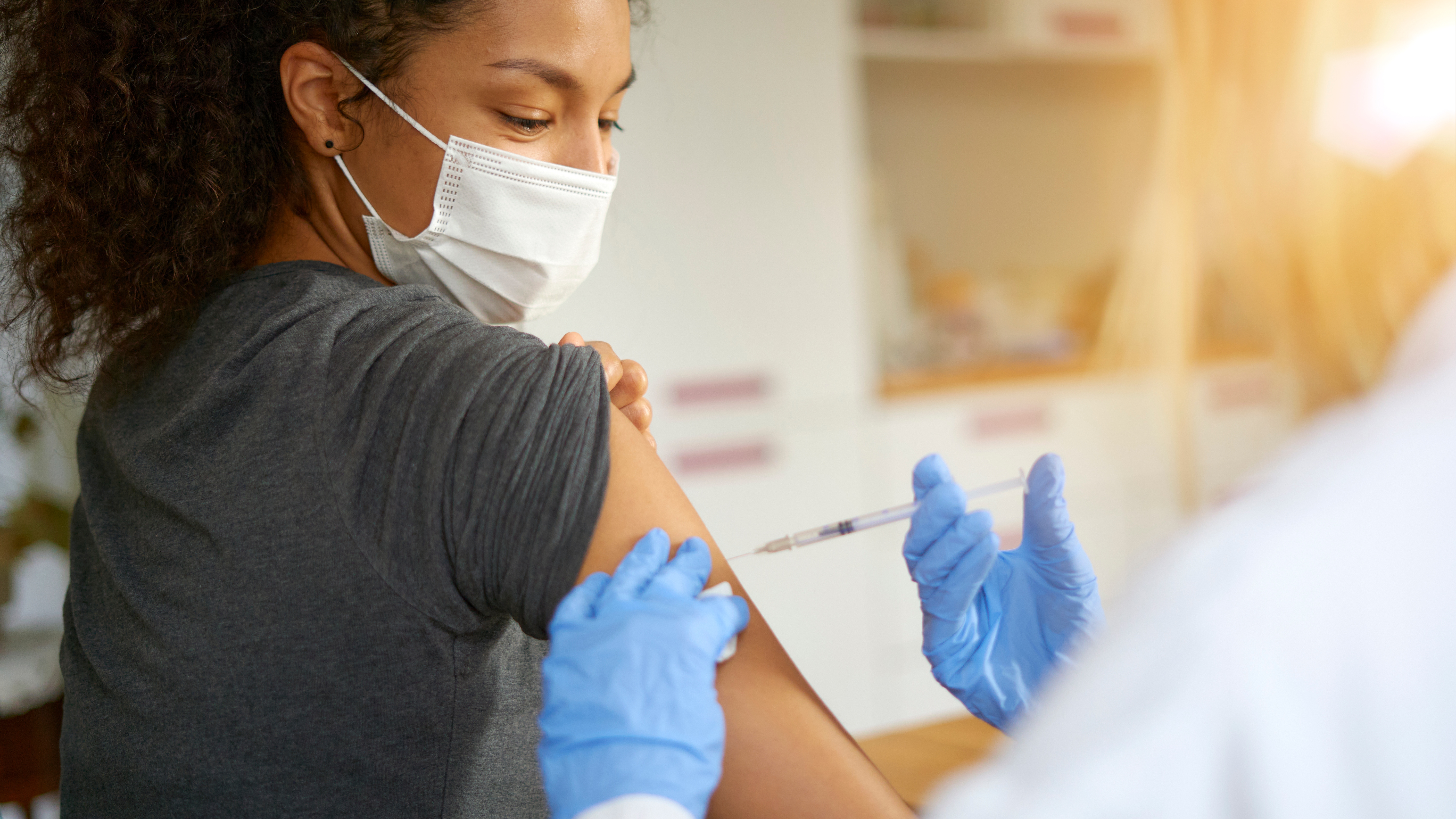 Close-up portrait of a beautiful young woman wearing a mask getting vaccinated.