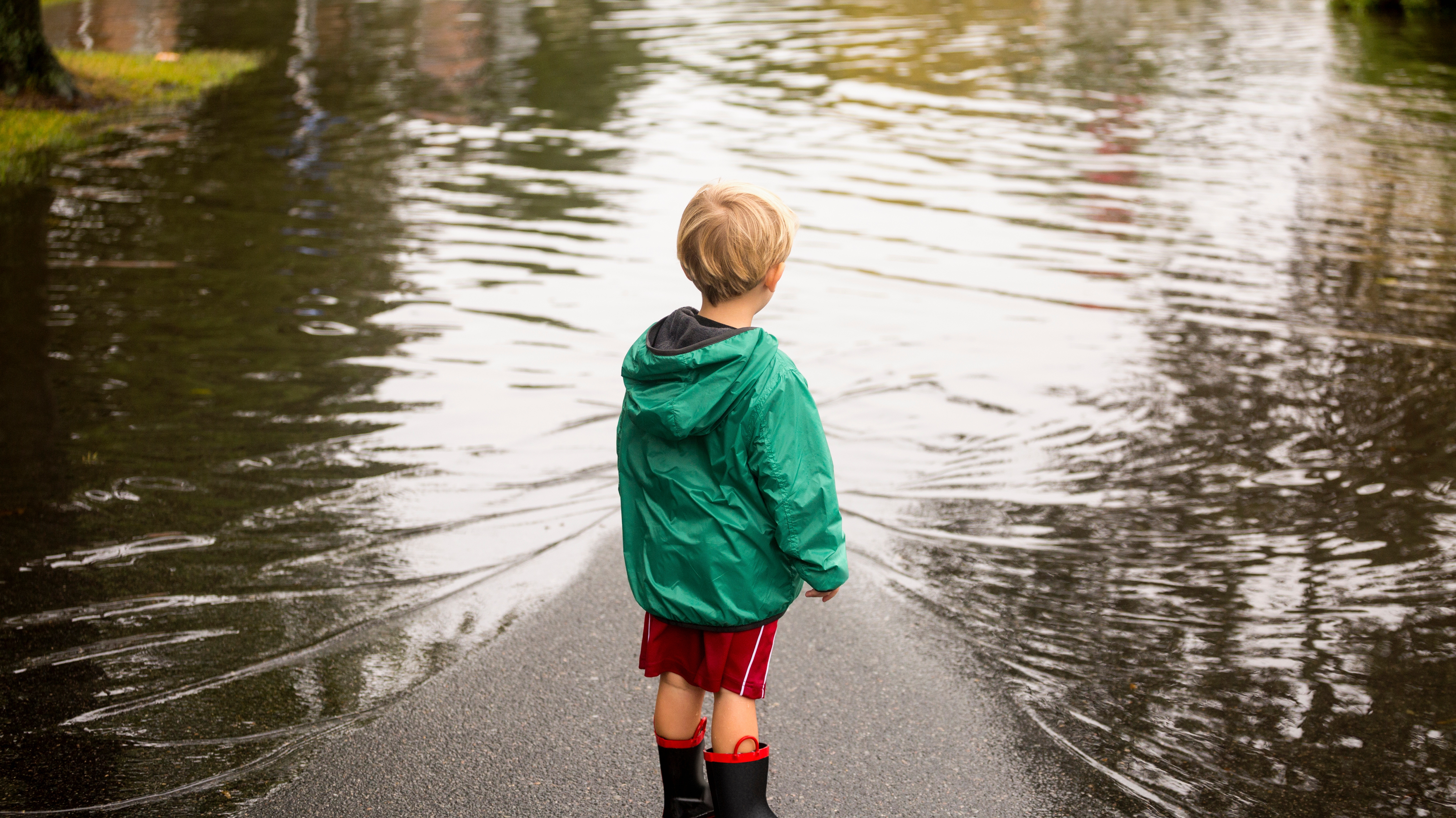 Caucasian boy wearing puddles near flood