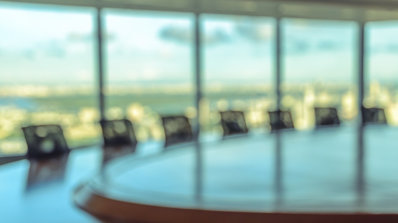 Management Blurred image of empty boardroom with window cityscape background.