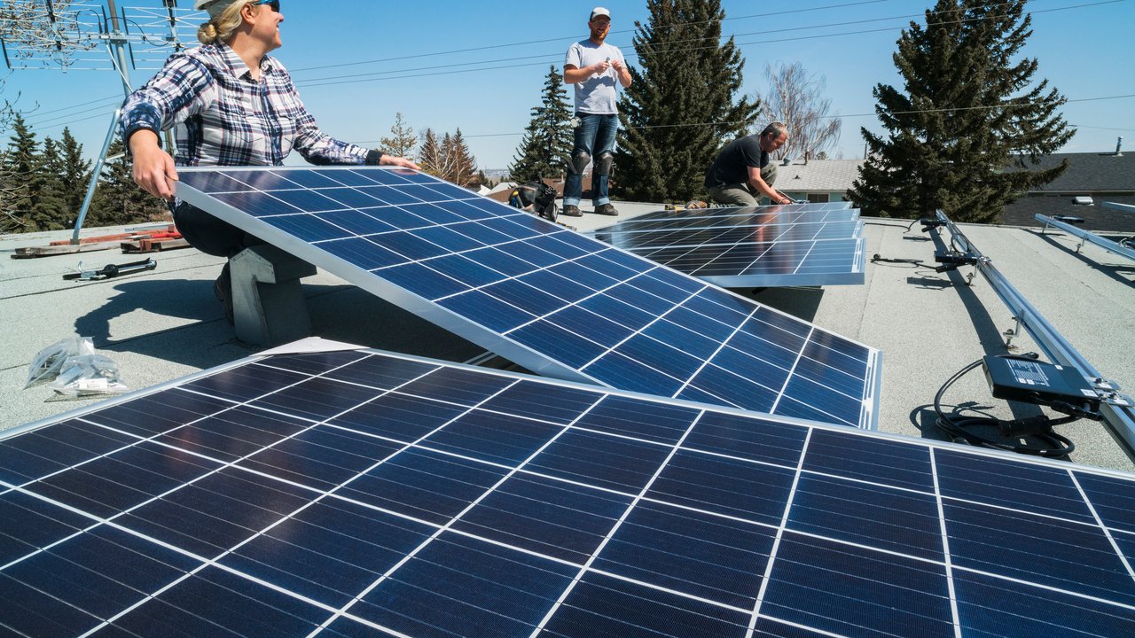 Reinsured Commercial Equipment Breakdown Workers installing solar panels on the roof of a residential building.